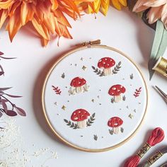 a close up of a embroidery on a table with scissors and flowers in the background