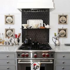 a stove top oven sitting inside of a kitchen next to a wall with pictures on it