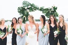 a group of women standing next to each other in front of a body of water