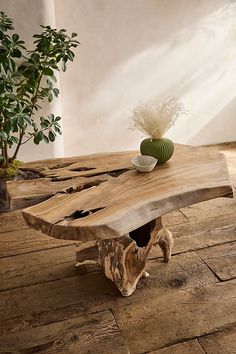 a table made out of wood with a vase on top and a plant in the middle