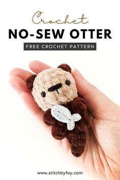 a hand holding a small crochet teddy bear with a bone in it's chest