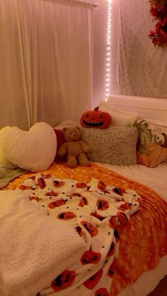 a bed covered in blankets and pillows with pumpkins on them