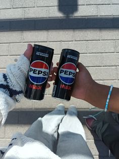 two people holding cans of pepsi on their hands