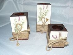 three wooden boxes with flowers on them tied up to each other, sitting on a white surface