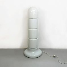 a white lamp sitting on top of a table next to a phone charger and plugged in