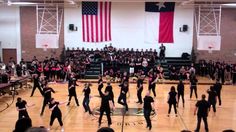 a group of people standing on top of a gym floor in front of an american flag