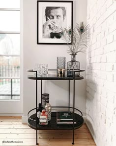 a black table with drinks on it in front of a brick wall and framed photograph