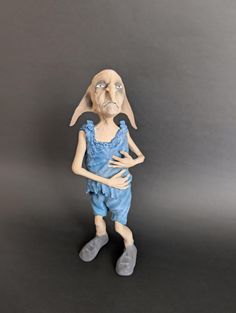 a ceramic figurine of a woman with her hands on her hips, standing against a gray background