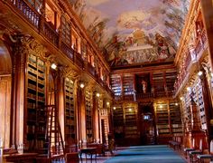 an ornate library with many bookshelves and paintings on the ceiling