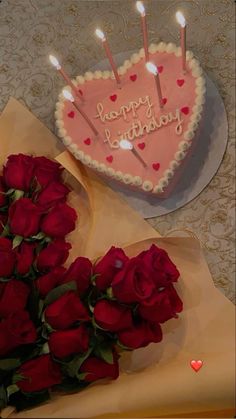 a heart shaped cake and bouquet of roses on a table next to a card that says happy birthday