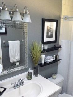 a white toilet sitting next to a bathroom sink under a mirror with lights on it