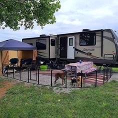 an rv parked on the side of a road next to a fence with a dog standing in front of it