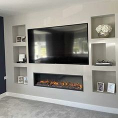 a living room with a large flat screen tv mounted on the wall next to a fire place