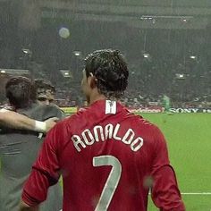 two soccer players shake hands at the end of a game on a rain soaked field