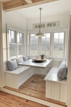 a window seat in the corner of a room with white walls and wood flooring