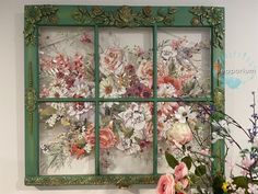 an old window is decorated with flowers and greenery on the outside, as well as a green frame