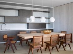 a dining room table with chairs and lights hanging from the ceiling