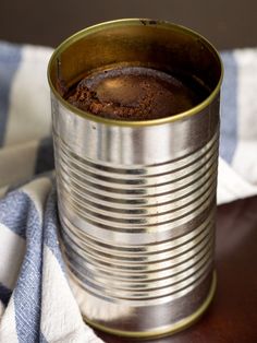 an open tin can sitting on top of a table next to a blue and white towel