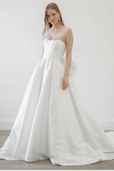 a woman in a white wedding dress posing for the camera with her hands on her hips