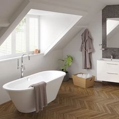 a white bath tub sitting under a bathroom window next to a sink and mirror in a room