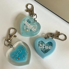 three heart shaped keychains with the words blue and white written on them are sitting next to each other