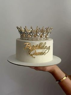 a woman is holding a birthday cake with a crown on top and the words happy birthday queen written on it