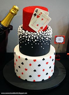 a three tiered cake decorated with playing cards and a bottle of champagne on top