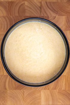 a bowl filled with batter sitting on top of a wooden table