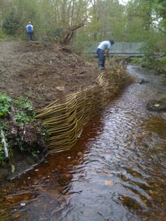 two men are working on the side of a stream