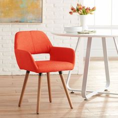 an orange chair sitting in front of a white table