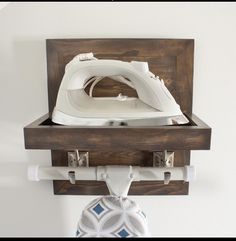 an ironing board mounted on a wall with a wooden shelf holding a white iron