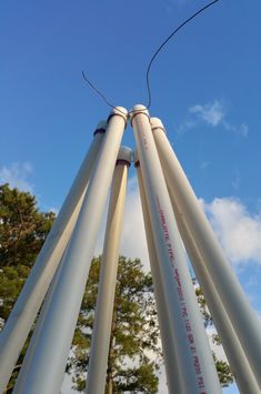 four large white pipes sticking out of the ground with trees in the backgroud