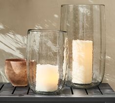 three glass vases sitting next to each other on top of a wooden table in front of a wall