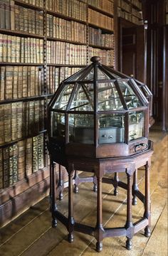 an old clock sitting on top of a wooden table in front of bookshelves