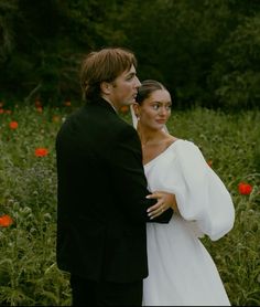 a bride and groom standing in a field of flowers