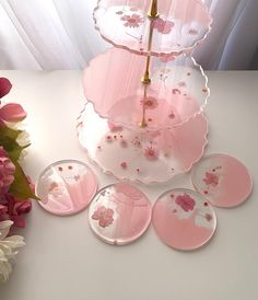 pink and white plates are arranged on a table with flowers in the vase next to it