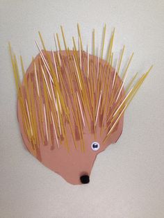 an animal made out of toothpicks on top of a white surface with yellow sticks sticking out of it's head