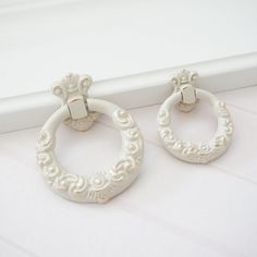 two pairs of white earrings sitting next to each other