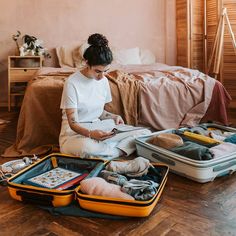 a woman is sitting on the floor with her suitcases full of clothes and other items