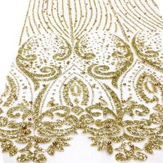 gold sequins and beads on white fabric with an intricate design in the center