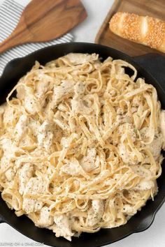 chicken alfredo in a skillet with bread on the side