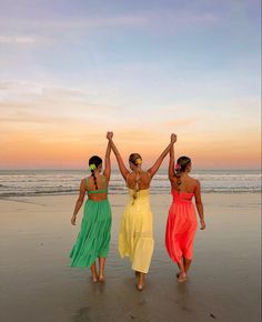 three women walking on the beach with their arms in the air