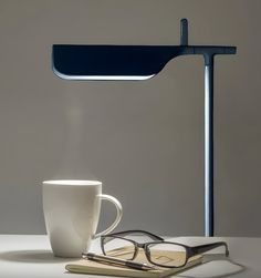 a pair of reading glasses sitting on top of a table next to a coffee cup