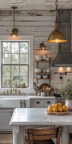 a kitchen with white walls and wooden floors, two pendant lights over the island counter