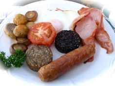 a white plate topped with sausages, tomatoes and other foods