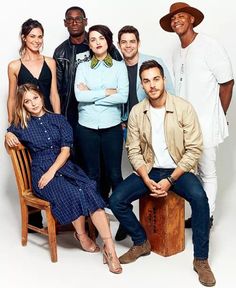 a group of people standing and sitting next to each other in front of a white background