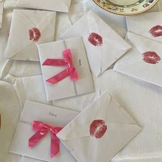 several envelopes with red lipstick on them and pink ribbon tied around the envelopes