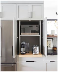 a kitchen with white cabinets and stainless steel appliances in the cupboards, including a coffee maker