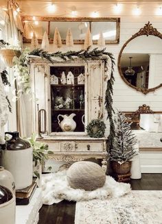 a room decorated for christmas with white furniture and garlands on the mantle, mirror, potted plants and other decorations