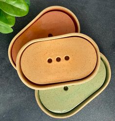 three ceramic bowls are stacked on top of each other with holes in the middle to show buttons